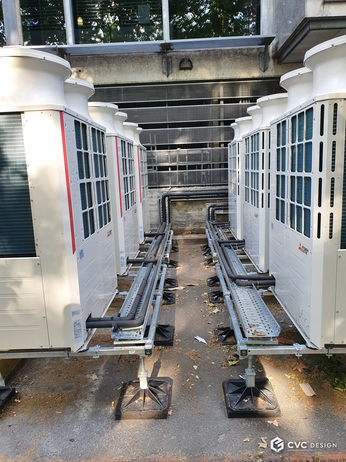 Deux rangées de groupes extérieurs VRV Mitsubishi City Multi installées en vis-à-vis, liaisons frigorifiques sur chemins de câbles centraux, sur plots anti-vibratiles — Préfecture de Bobigny